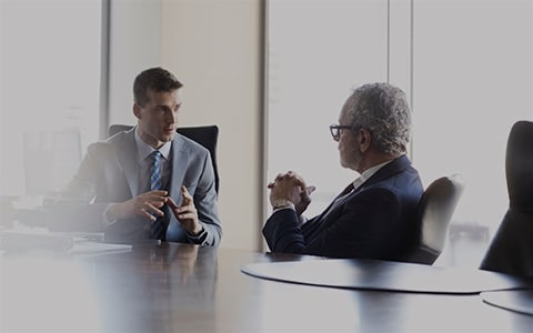 Two male professionals talking at table